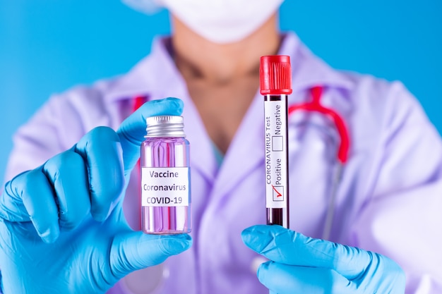 Doctor holds COVID 19  vaccine, blood test tube in her hand. Vaccine it use for prevention COVID-19.