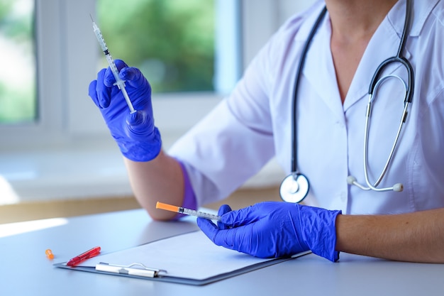 Doctor holds insulin injection syringe for diabetes patient during medical consultation and examination in hospital. Healthcare and chronic disease treatment