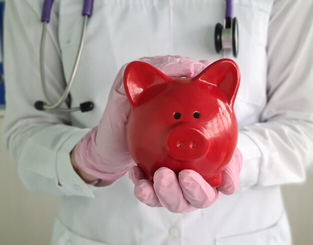 Doctor holds piggy bank of financial medical savings in hands