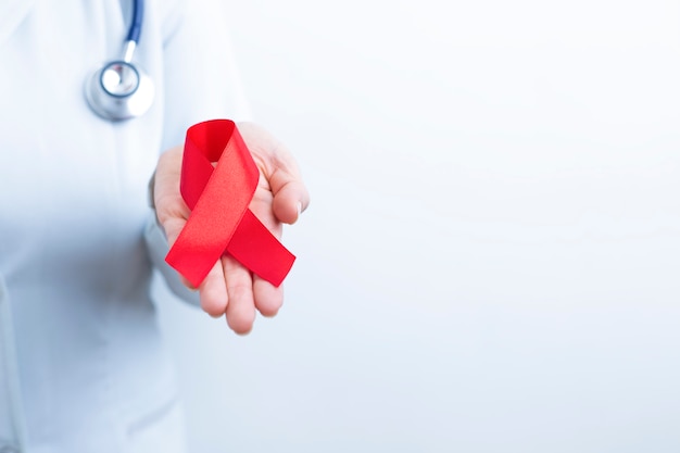 Doctor holds red ribbon symbol of the fight against AIDS