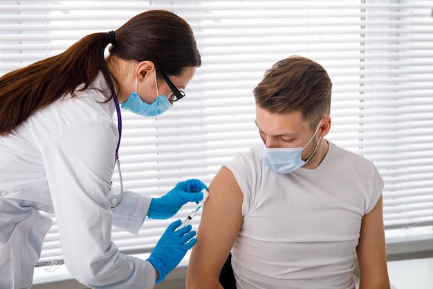 The doctor holds a syringe before giving an injection to a patient in a medical mask Covid19 or coronavirus vaccine