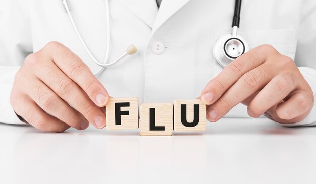 Doctor holds wooden cubes in his hands with text FLU