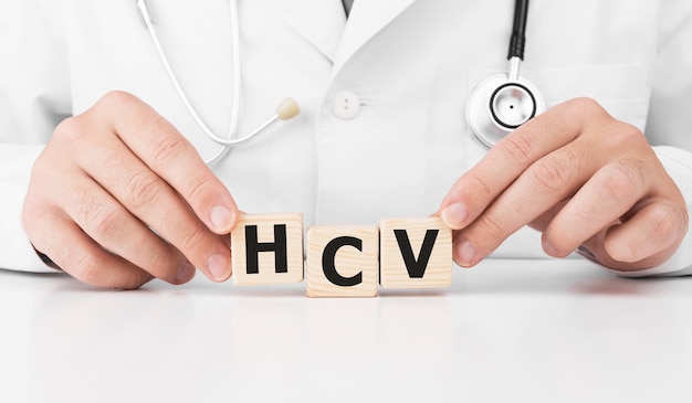 Doctor holds wooden cubes in his hands with text HCV