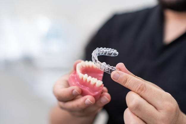 Doctor installing clear aligners on plastic human jaw model to show simple and effective device