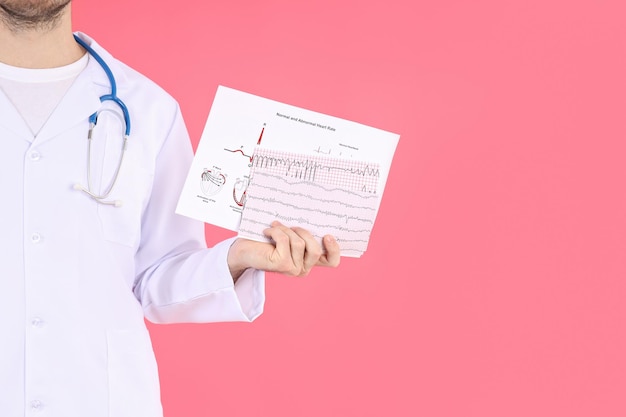 Doctor - intern with cardiogram on pink background