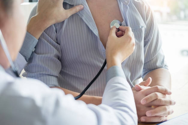 Doctor is checking on patient's chest uses stethoscope to listen patient heart rate 