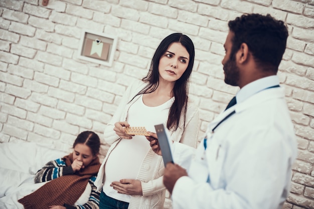 Doctor is giving pills to young pregnant mother.