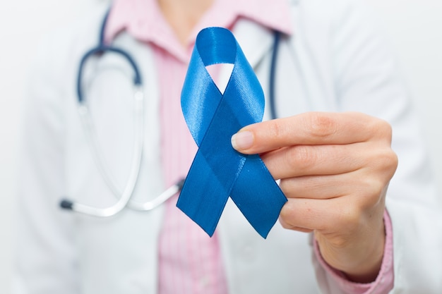 The doctor is holding a blue ribbon in his hand. The concept of prostate cancer. 