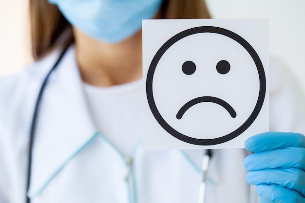 The doctor is holding a card with the Sad Smile symbol in the office of the clinic