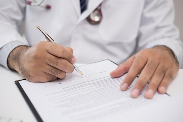 The doctor is working on the paperwork he checks the patients condition checks the items and makes notes on the notepad