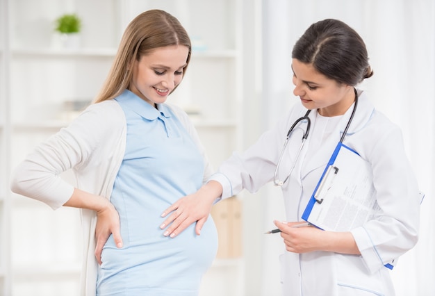 Doctor keeping hand on the tummy of her pregnant patient.