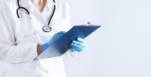 Doctor in a lab coat with folder making notes over white background