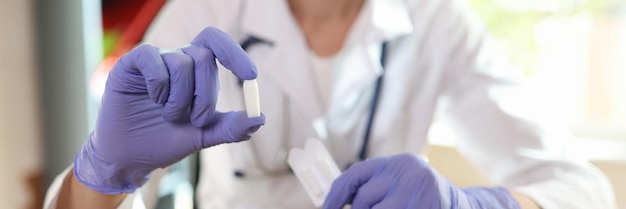 Doctor in latex gloves shows suppositories for anal or vaginal use close up of medical candles