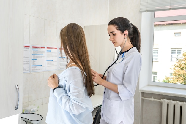 Doctor listening patient's breathing on back close up