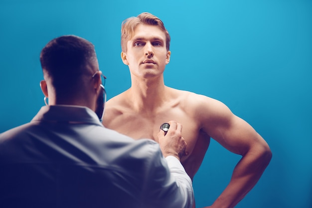 Doctor listening with stethoscope to patient in medical office