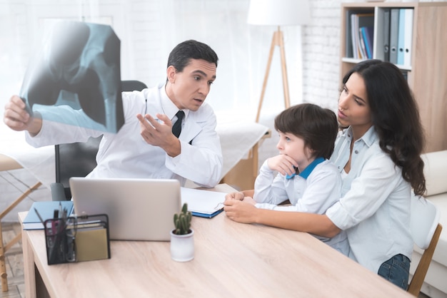 The doctor looks at the X-ray of the child.