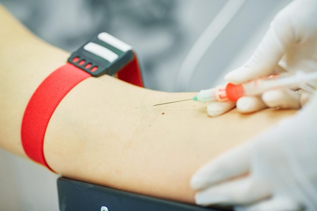 The doctor makes an injection in the vein and arm of the patient closeup