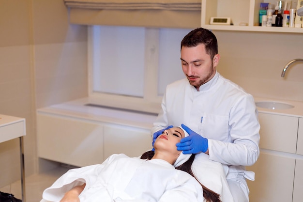 Doctor makes a markup on the face of a beautiful female before the comet procedure for correcting the shape of the face