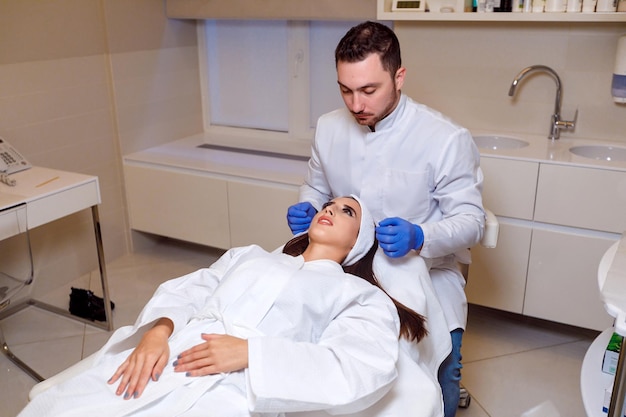 Doctor makes a markup on the face of a beautiful female before the comet procedure for correcting the shape of the face