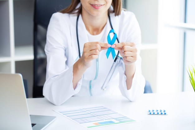 Doctor man holding light blue ribbon for supporting people living and illness