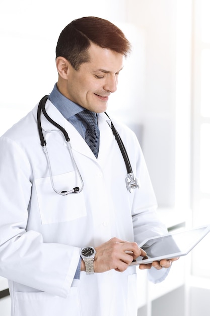 Doctor man using tablet computer for network research or virtual disease treatment. Perfect medical service in clinic. Happy future for modern medicine, medic data and healthcare concepts