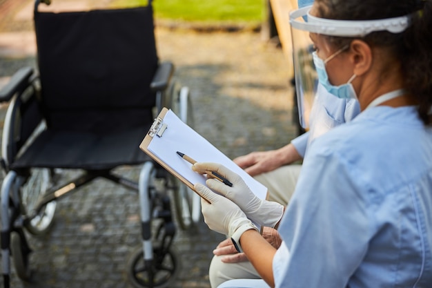 Doctor in mask and protection helmet showing the files