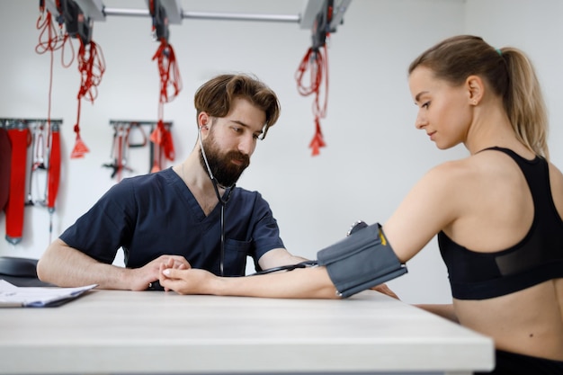 Doctor measures blood pressure in a young sports woman