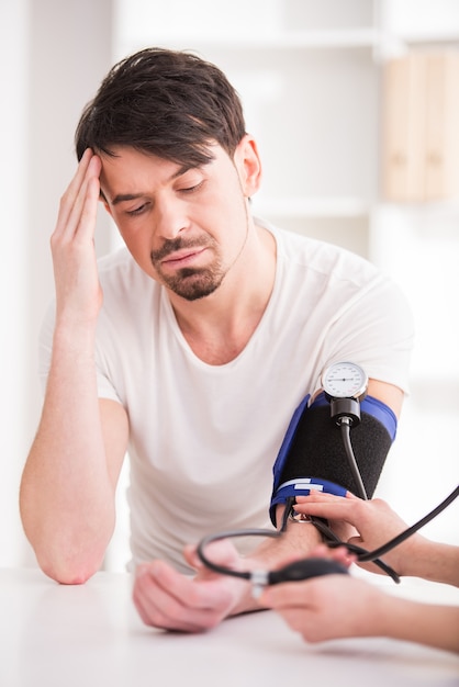 Doctor measures the pressure to young man with headache.