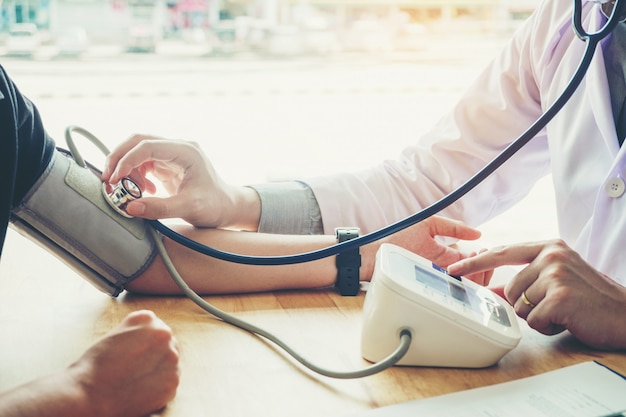 Doctor Measuring arterial blood pressure woman patient on right arm 