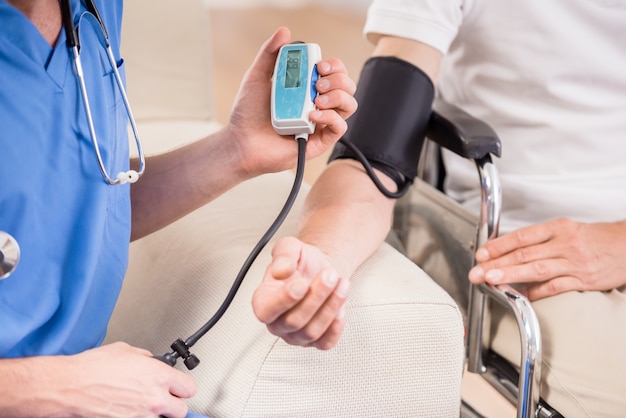 Doctor measuring blood pressure to older patient.