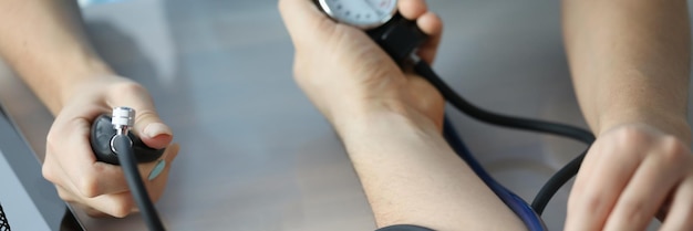 Doctor measuring patient blood pressure on arm using tonometer closeup