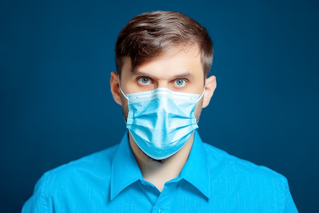 A doctor in a medical mask and gloves, dressed in a blue uniform