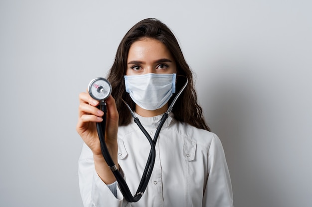 Doctor in medical mask with phonendoscope does auscultation to patient. Medical therapy and treatment. Research and testing for coronavirus covid-19