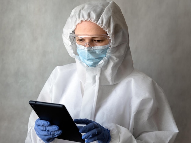 Photo doctor in medical ppe suit uses digital tablet