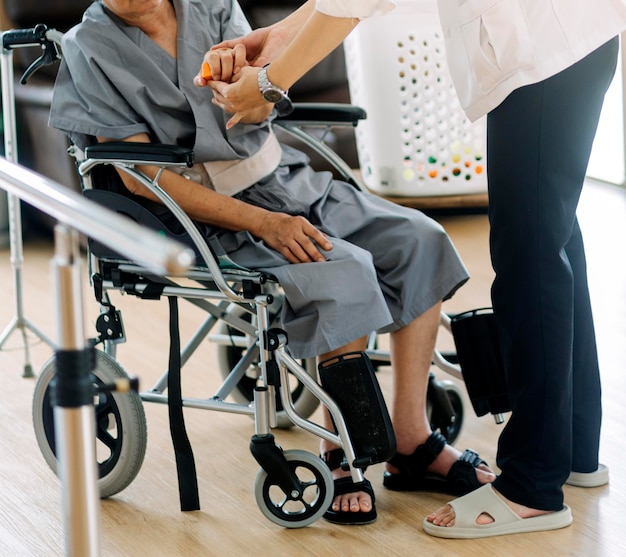 Doctor or nurse caregiver with senior man in a wheelchair wearing protective masks at home or nursing home