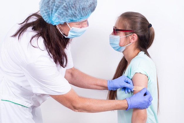 Doctor or nurse glues bandage on patients shoulder after an injection or vaccination closeup vaccina...