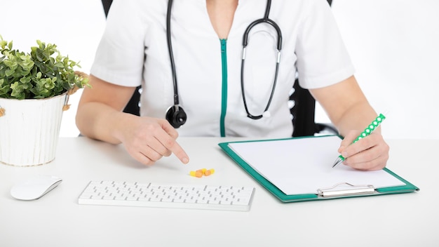 Doctor, nurse at her desk with documents and pointing out pills.