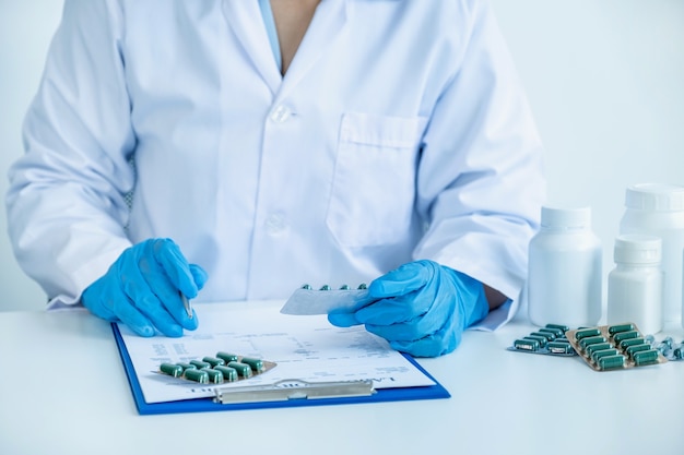 doctor or nurse holding medicine pill and write prescription at pharmacy office medical checkup