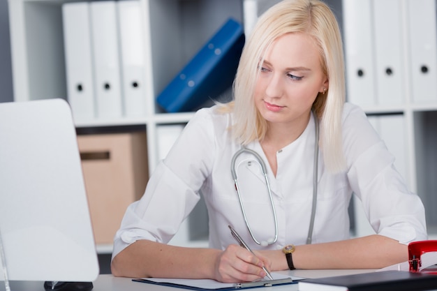 Doctor in the office makes a record in the reception log