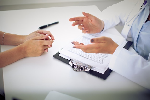 Doctor and patient are discussing something, just hands at the table.