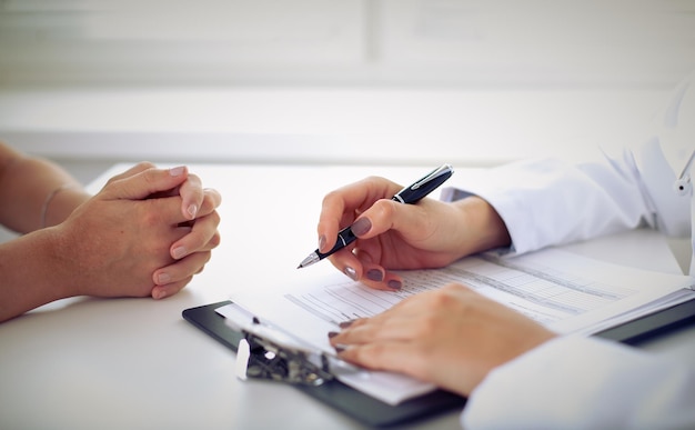 Doctor and patient are discussing something, just hands at the table.