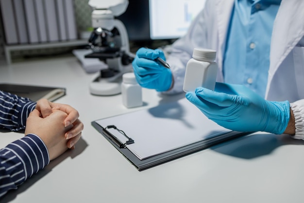 Doctor and patient in conversation about pill description professional physician wearing white coat talking to mature woman signing medical paper at appointment