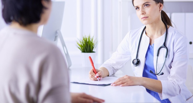 Doctor and patient discussing medical problems in a hospital consulting room Doc filling in a patient's form