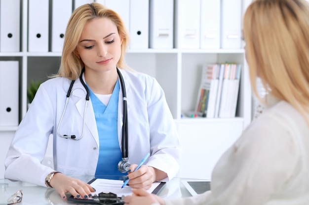 Doctor and  patient  discussing something while sitting at the table . Medicine and health care concept