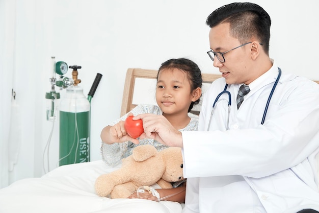 Doctor and patient holding heart shape at home