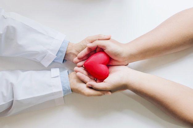 Doctor and the patient holding a red heart together.