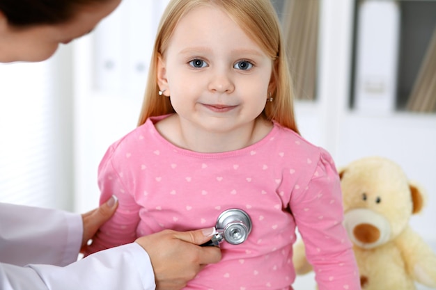 Photo doctor and patient in hospital child being examined by physician with stethoscope