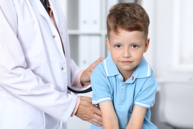 Doctor and patient in hospital Happy little boy having fun while being examined with stethoscope Healthcare and insurance concept