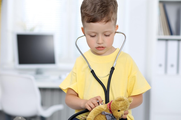 Doctor and patient in hospital Happy little boy having fun while being examined with stethoscope Healthcare and insurance concept