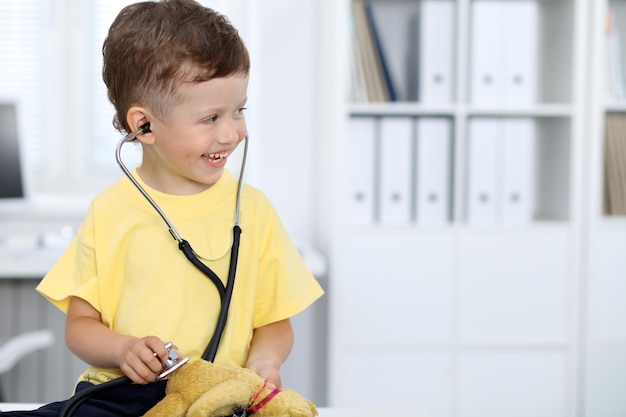 Doctor and patient in hospital Happy little boy having fun while being examined with stethoscope Healthcare and insurance concept